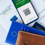 Still life of a digital COVID certificate, passports, and a leather wallet for travel documentation.